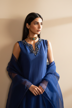 Blue top with intricate beadwork and a person wearing it against a neutral background